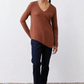 Rust-brown V-neck long-sleeve top worn with dark jeans and sneakers