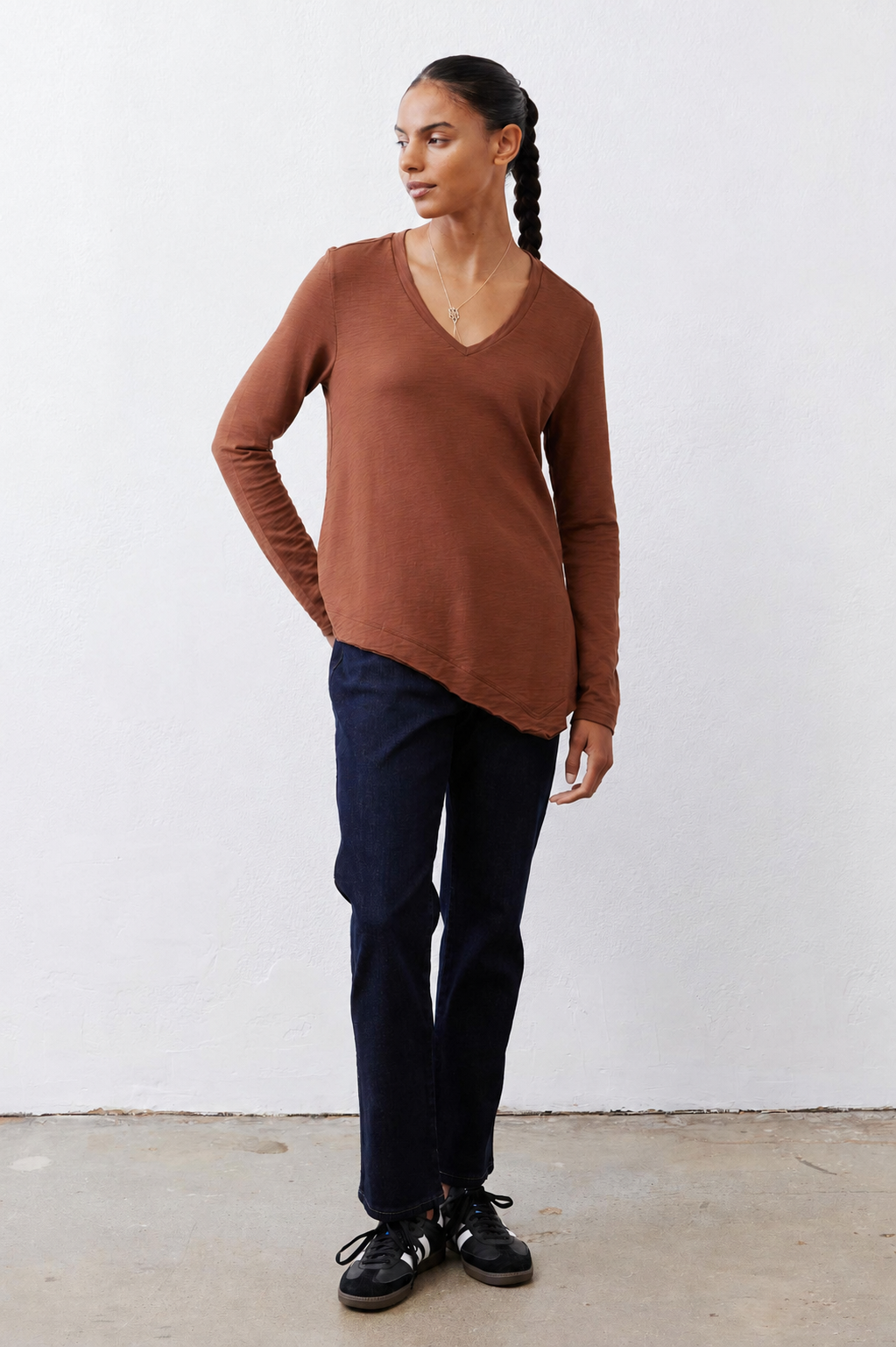 Rust-brown V-neck long-sleeve top worn with dark jeans and sneakers