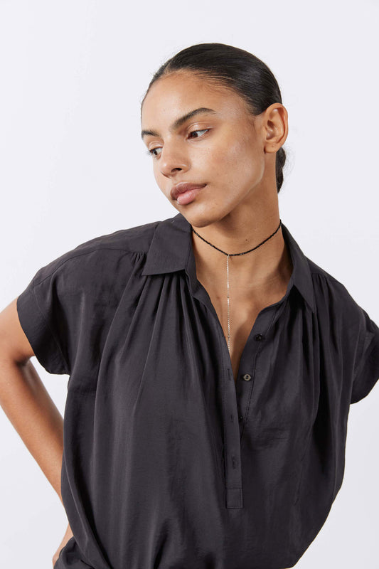 Black voile blouse close-up with gathered shoulder yoke and button-front neckline.