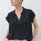 Black oversized silk blouse with short sleeves, button front, and pointed collar.