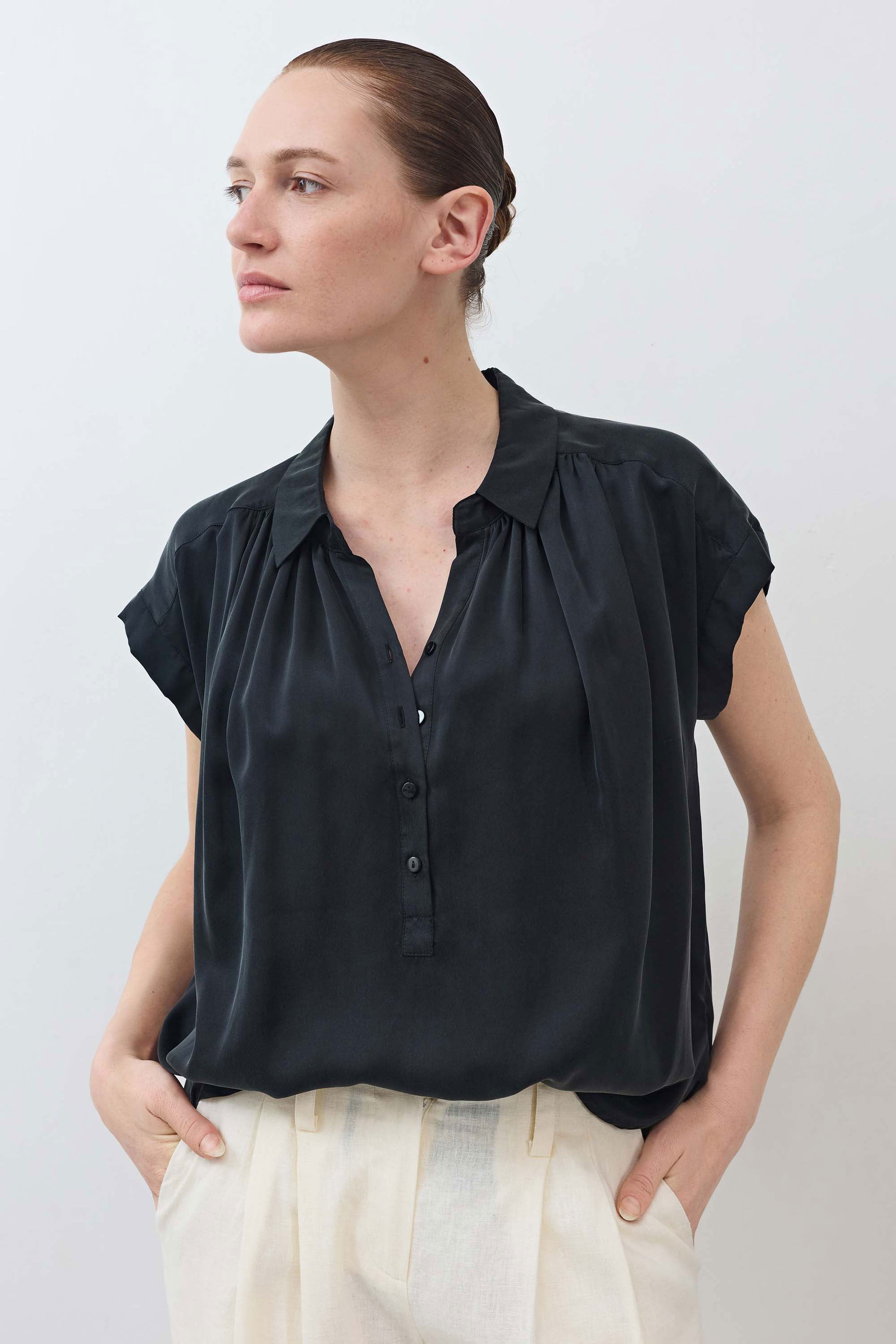 Black oversized silk blouse with short sleeves, button front, and pointed collar.