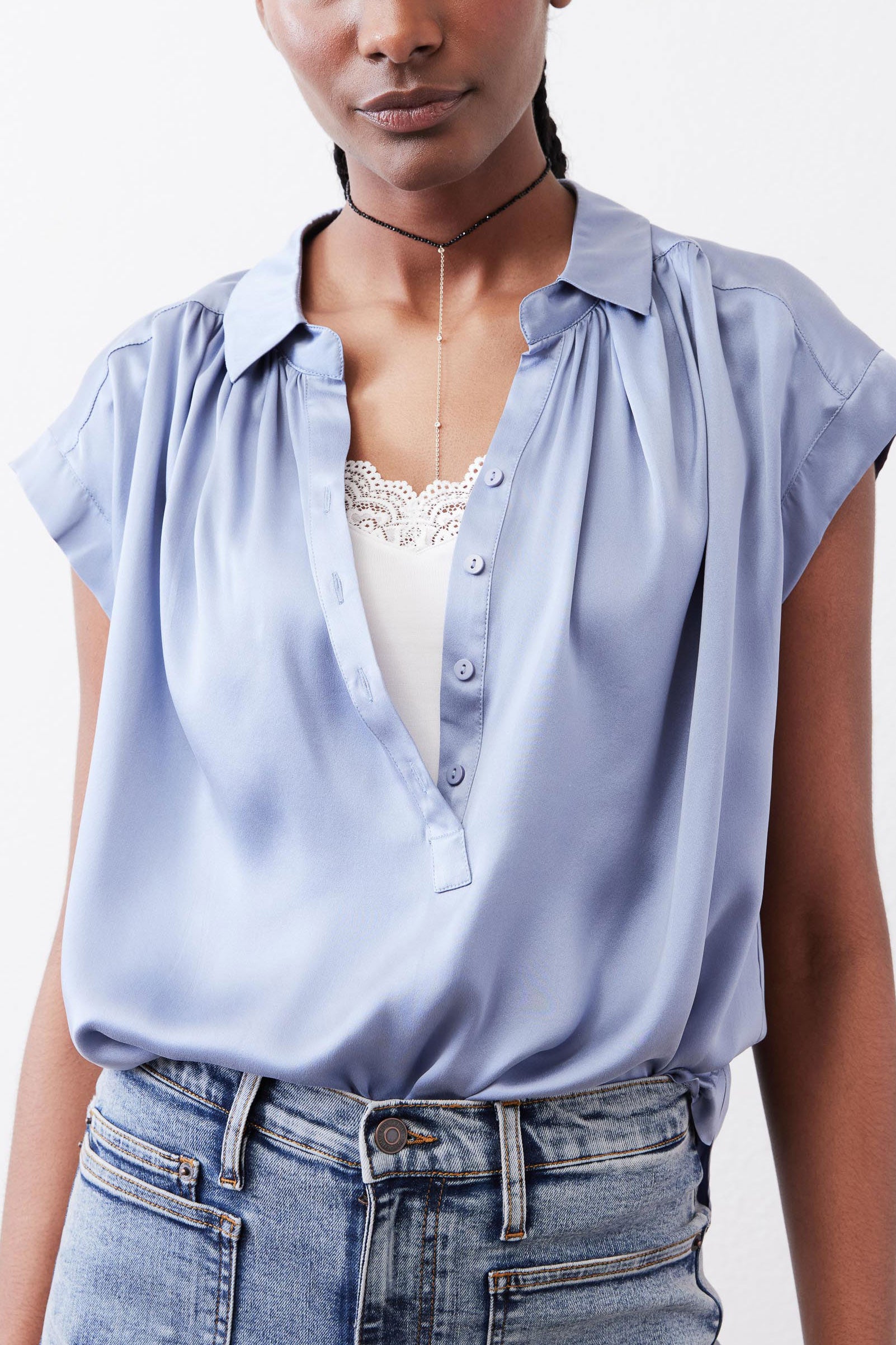 Steel blue silk blouse front with V-neck button placket and lace-trim neckline.