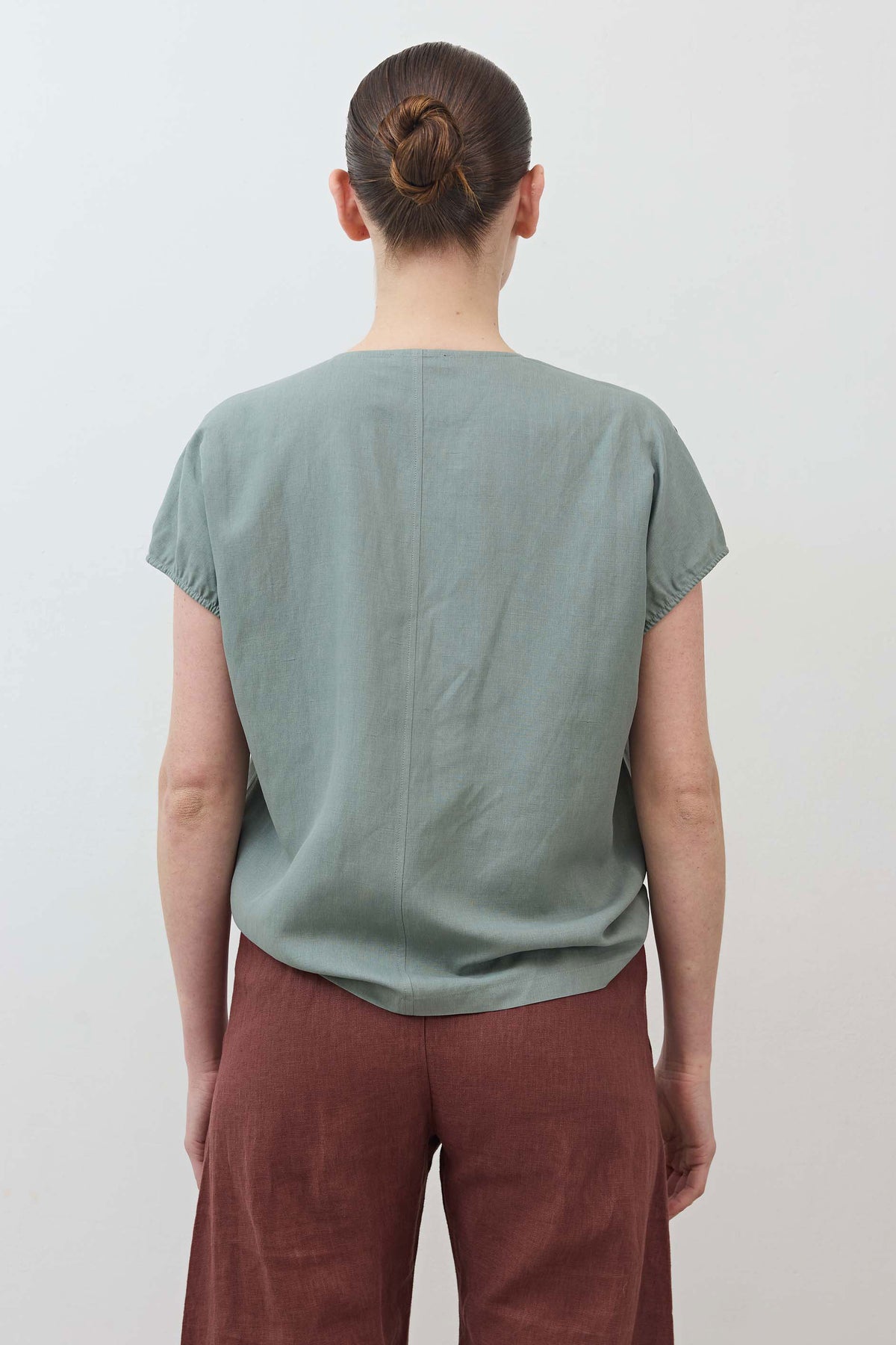Back view of muted green V-neck silk-linen top with short sleeves.