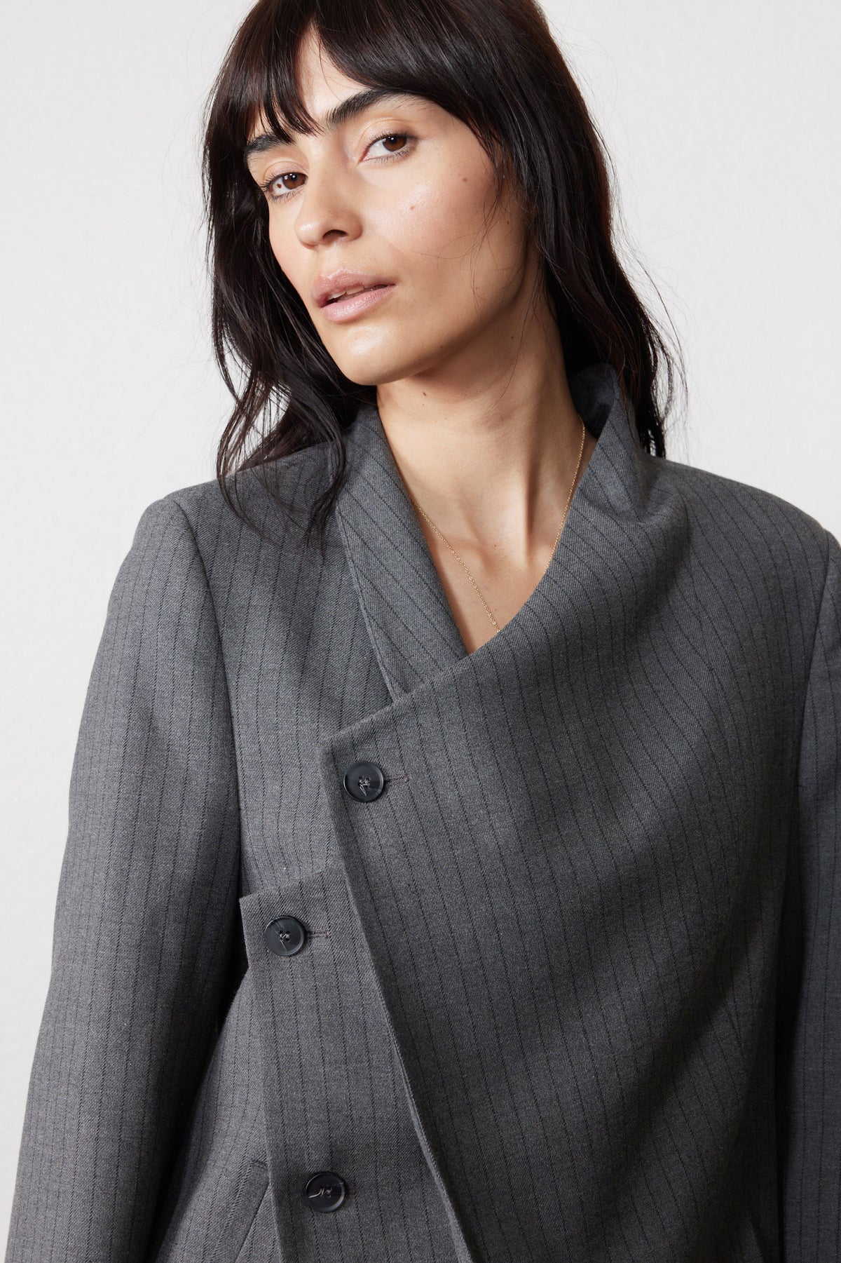 Gray pinstripe asymmetric suit jacket close-up with double-breasted placket and collar