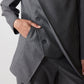 Gray pinstripe asymmetric suit jacket detail with buttoned flap and angled front panel