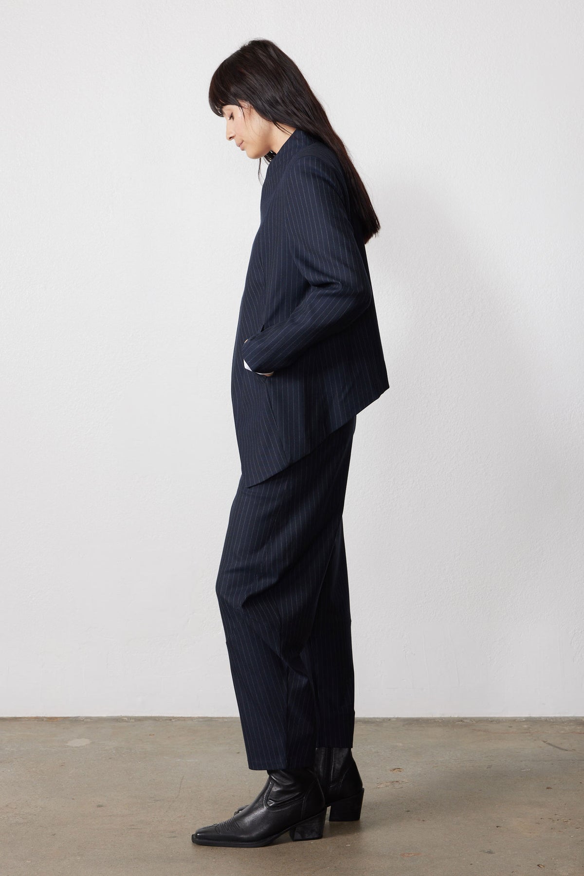 Navy pinstripe asymmetric suit jacket, side view, angled hem, long sleeves
