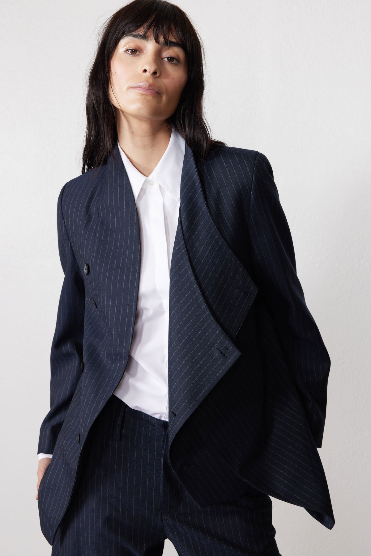 Navy pinstripe asymmetric suit jacket with draped lapel and button placket detail