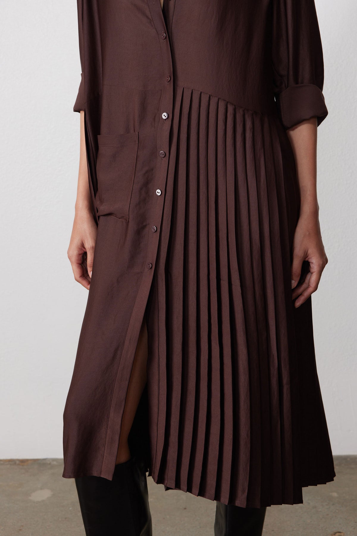 Close-up of dark brown dress: button placket with pleated side panel and side slit