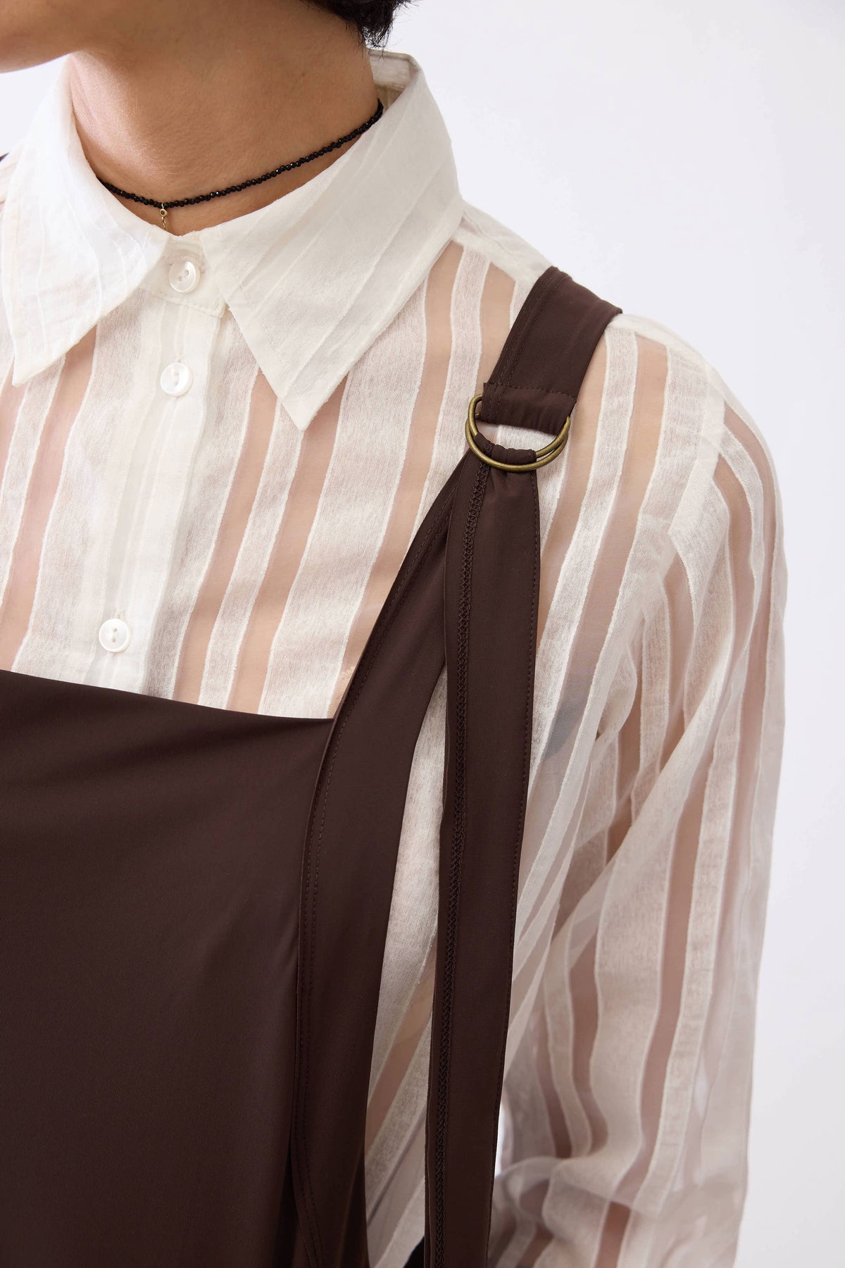 Detail of coffee-brown sarafan dress bodice with neckline trim and strap join