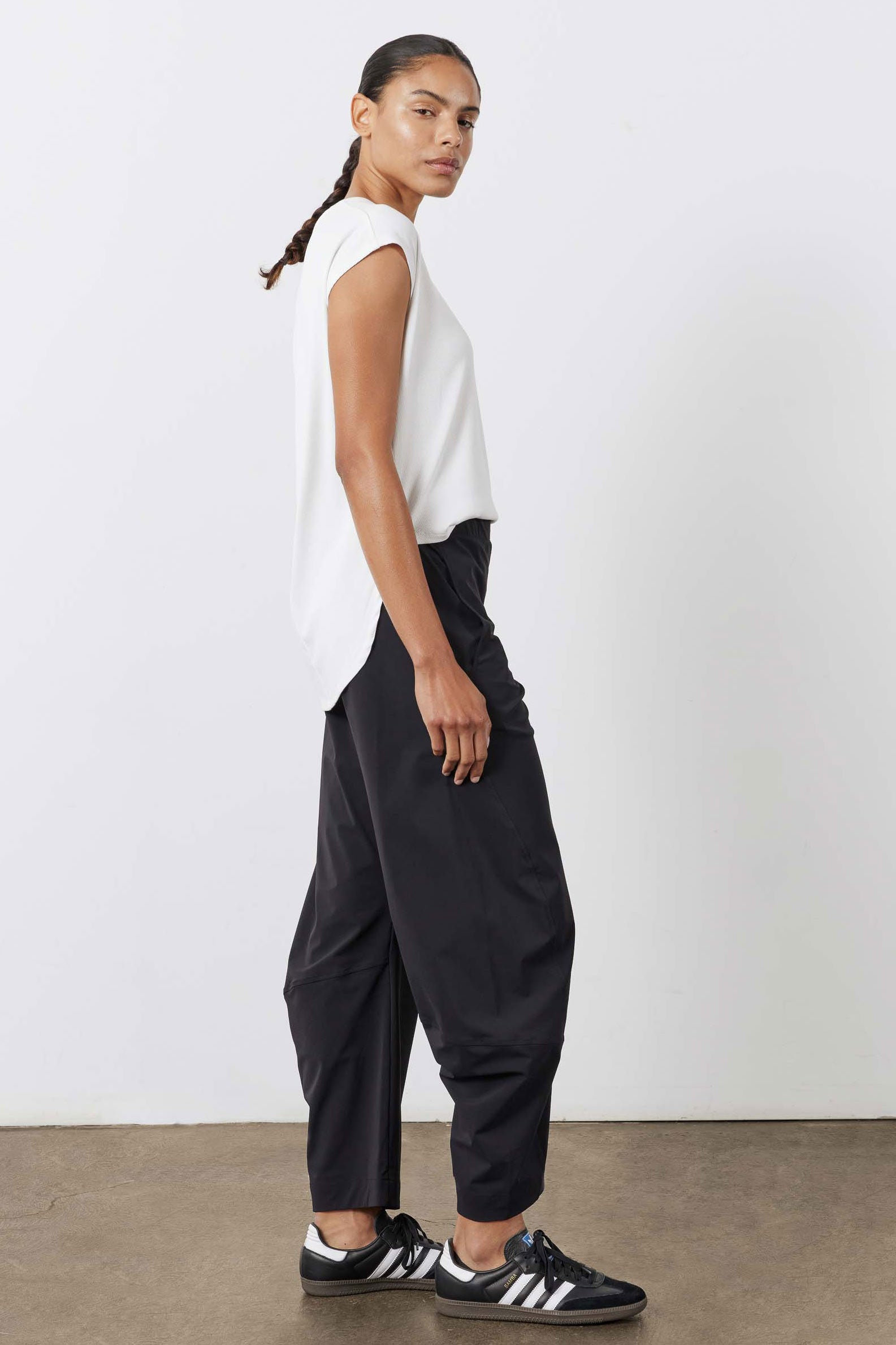 Black work pants with relaxed wide legs and elastic waistband, side profile view