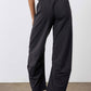 Black work pants with relaxed tapered wide legs and elastic waistband, walking side view