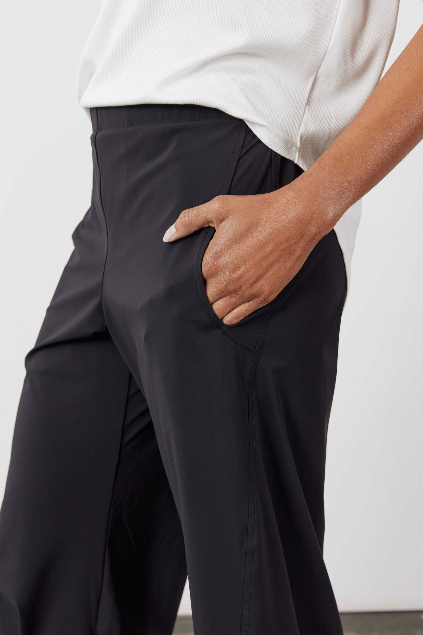 Black work pants with side pocket and elastic waistband, hand in pocket close-up