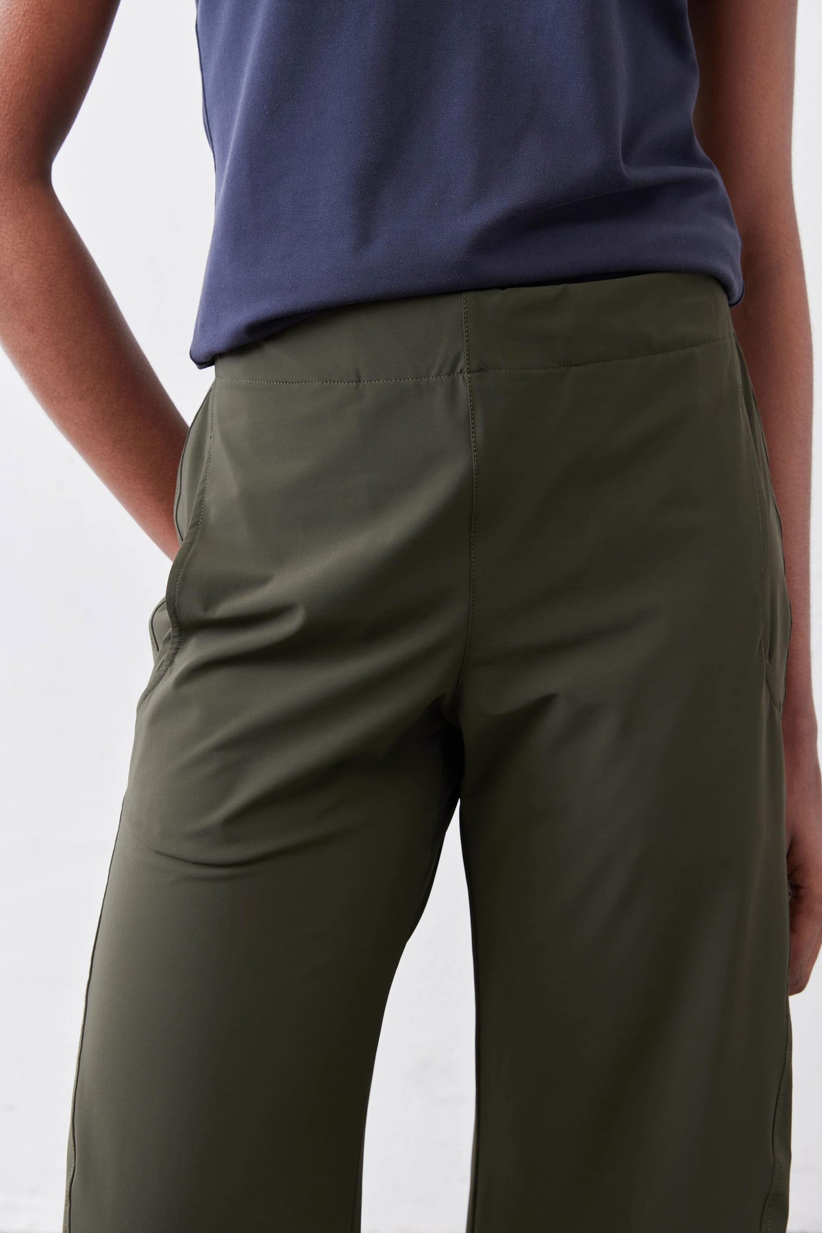 Olive green loose work pants with elastic waist and front seam detail, close-up