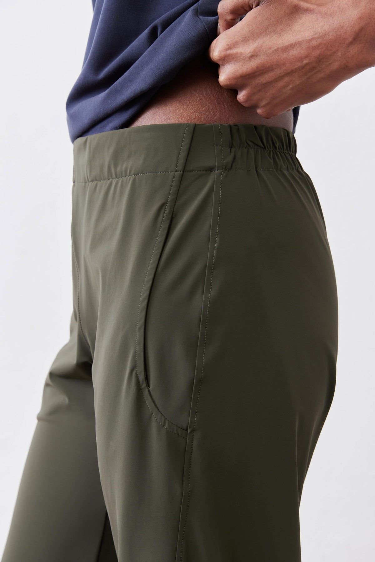 Olive green loose work pants with elastic waistband and side pocket, close-up