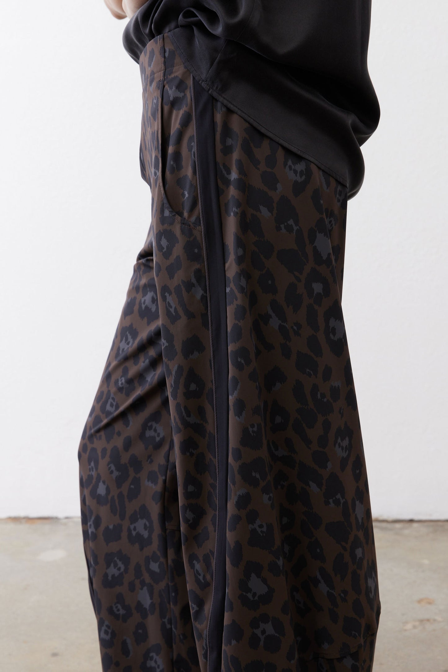 Draped dark leopard print fabric on loose work pants with gathered waist knot