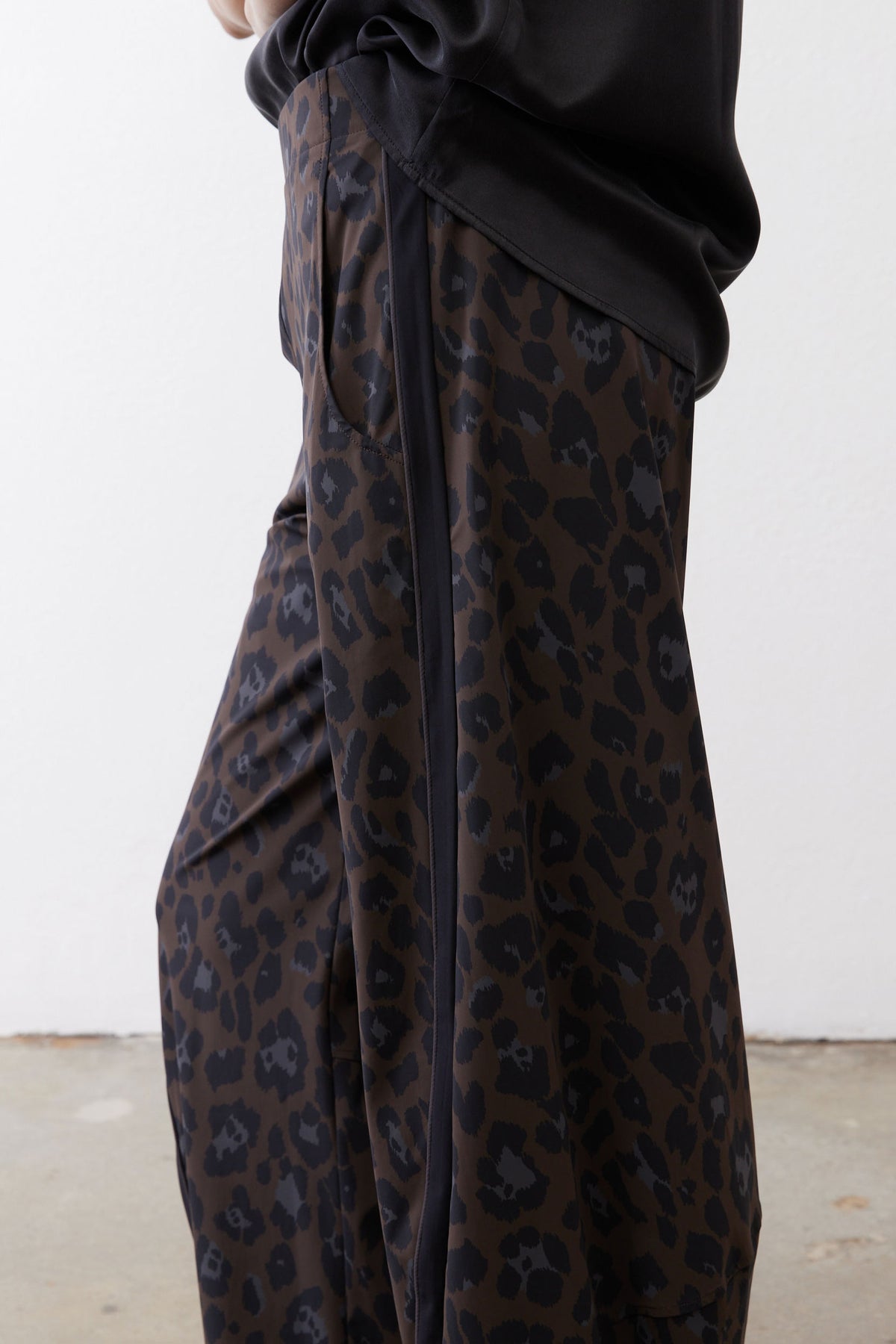 Draped dark leopard print fabric on loose work pants with gathered waist knot