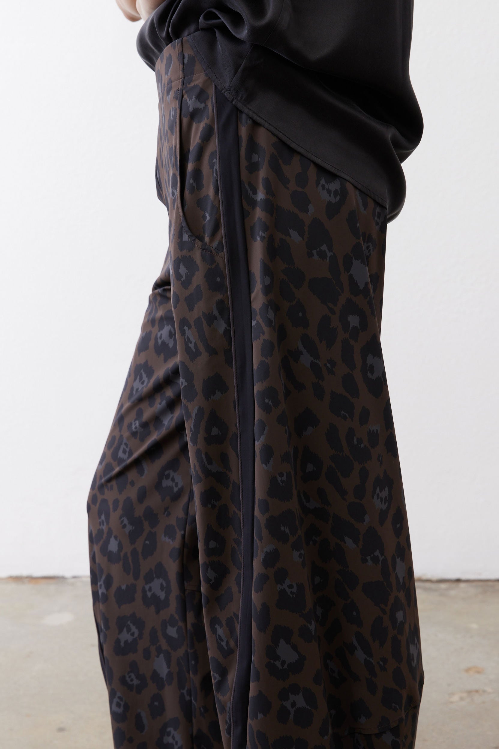 Draped dark leopard print fabric on loose work pants with gathered waist knot