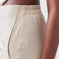Light beige loose work pants close-up showing elastic waistband and side seam stitching