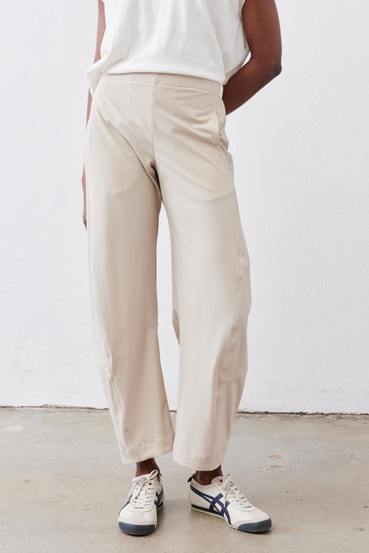 Loose light beige work pants with gathered elastic waistband and ankle cuffs.