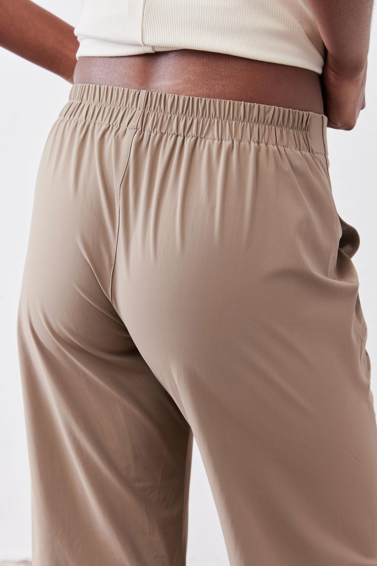 Tan pants close-up: elastic waistband with relaxed drape and smooth fabric texture