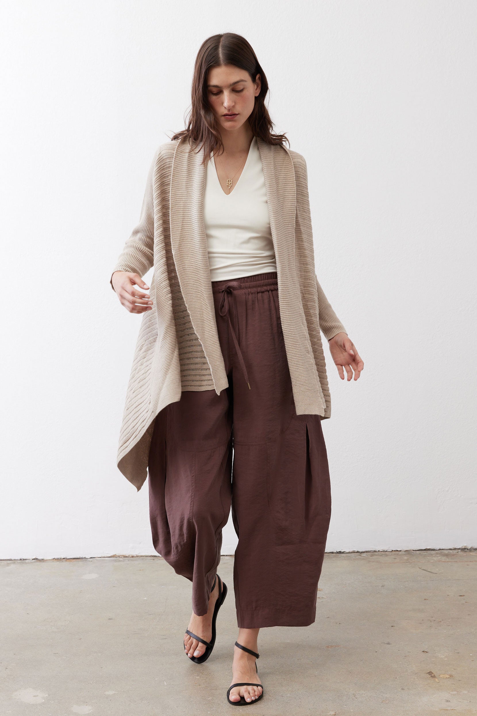 Light beige open knit cardigan with open front, long sleeves, and draped hem