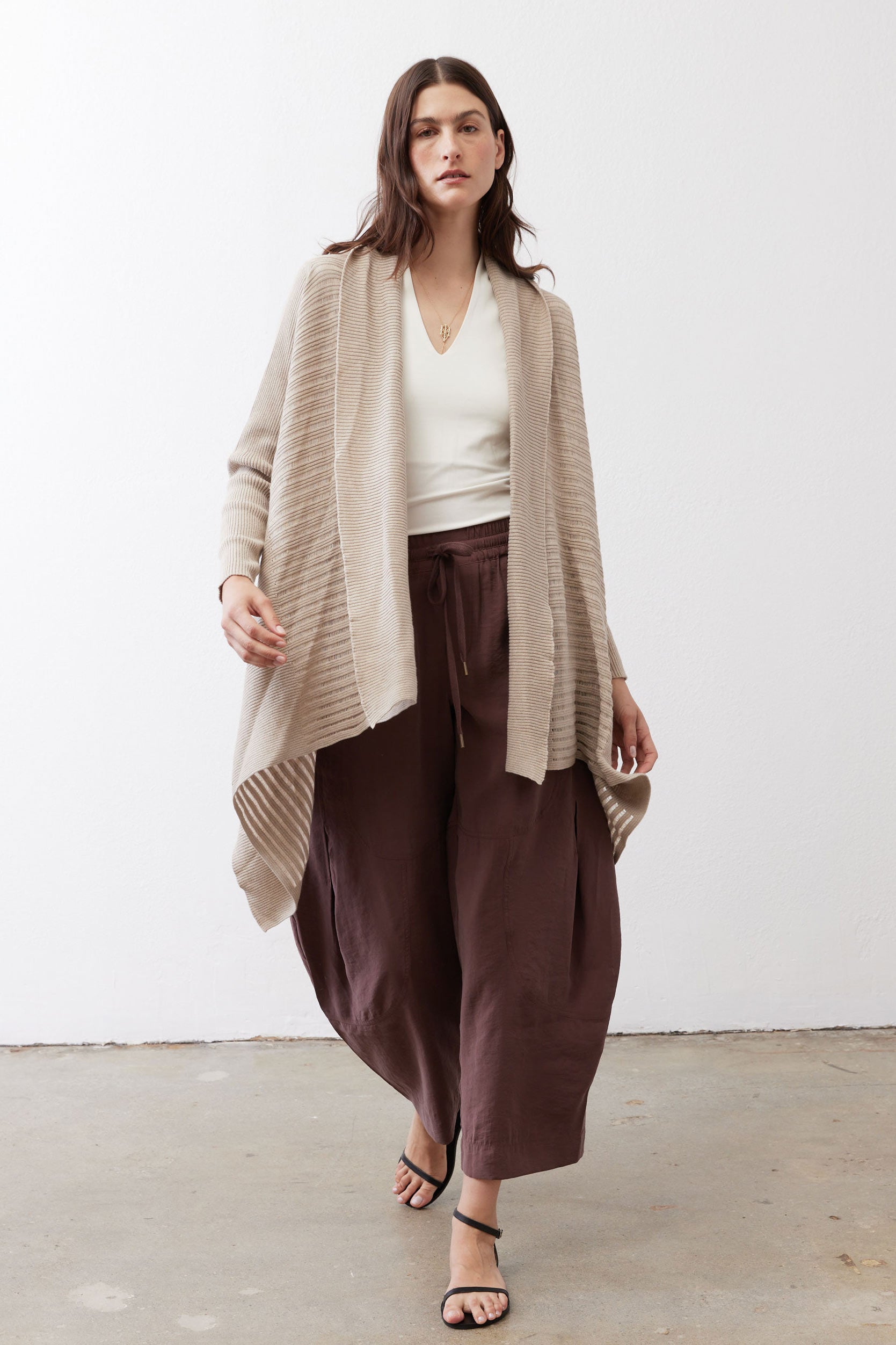 Open knit cardigan in light beige with open front, long sleeves, draped hem