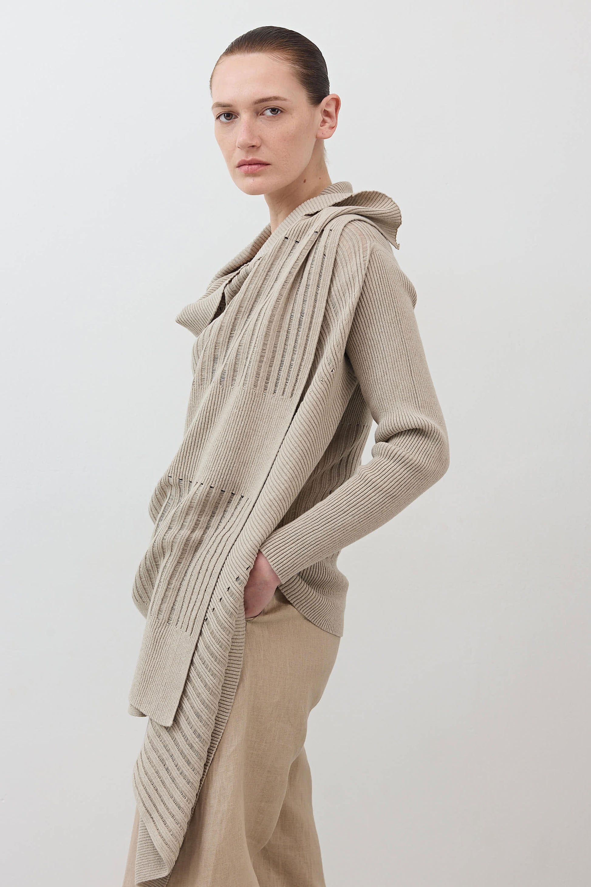 Open knit cardigan in light beige with draped front and long sleeves, angled view