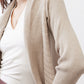 Close-up of light beige open knit cardigan texture and draped neckline