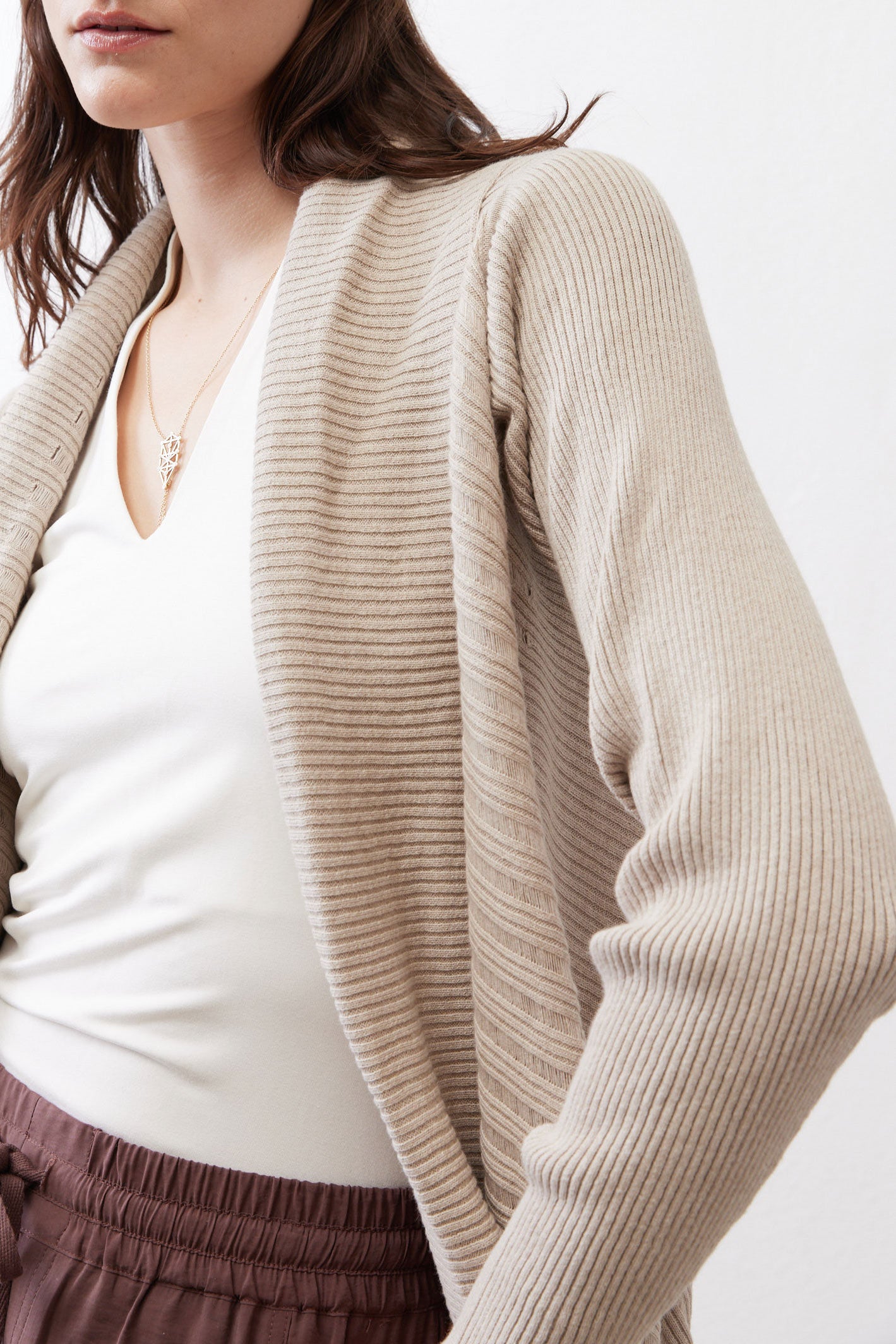 Close-up of light beige open knit cardigan texture and draped neckline