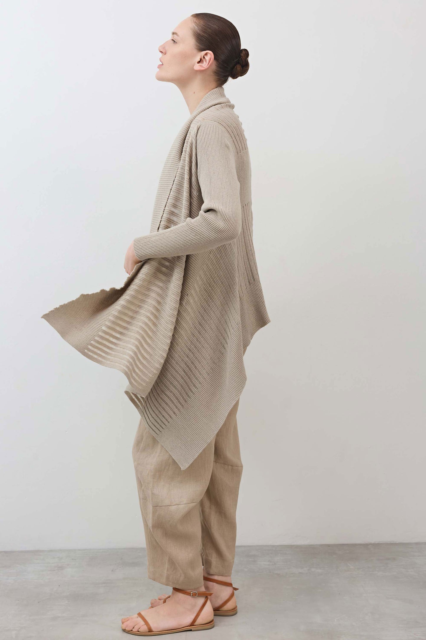 Open knit cardigan in light beige with draped front and wide hem, side view