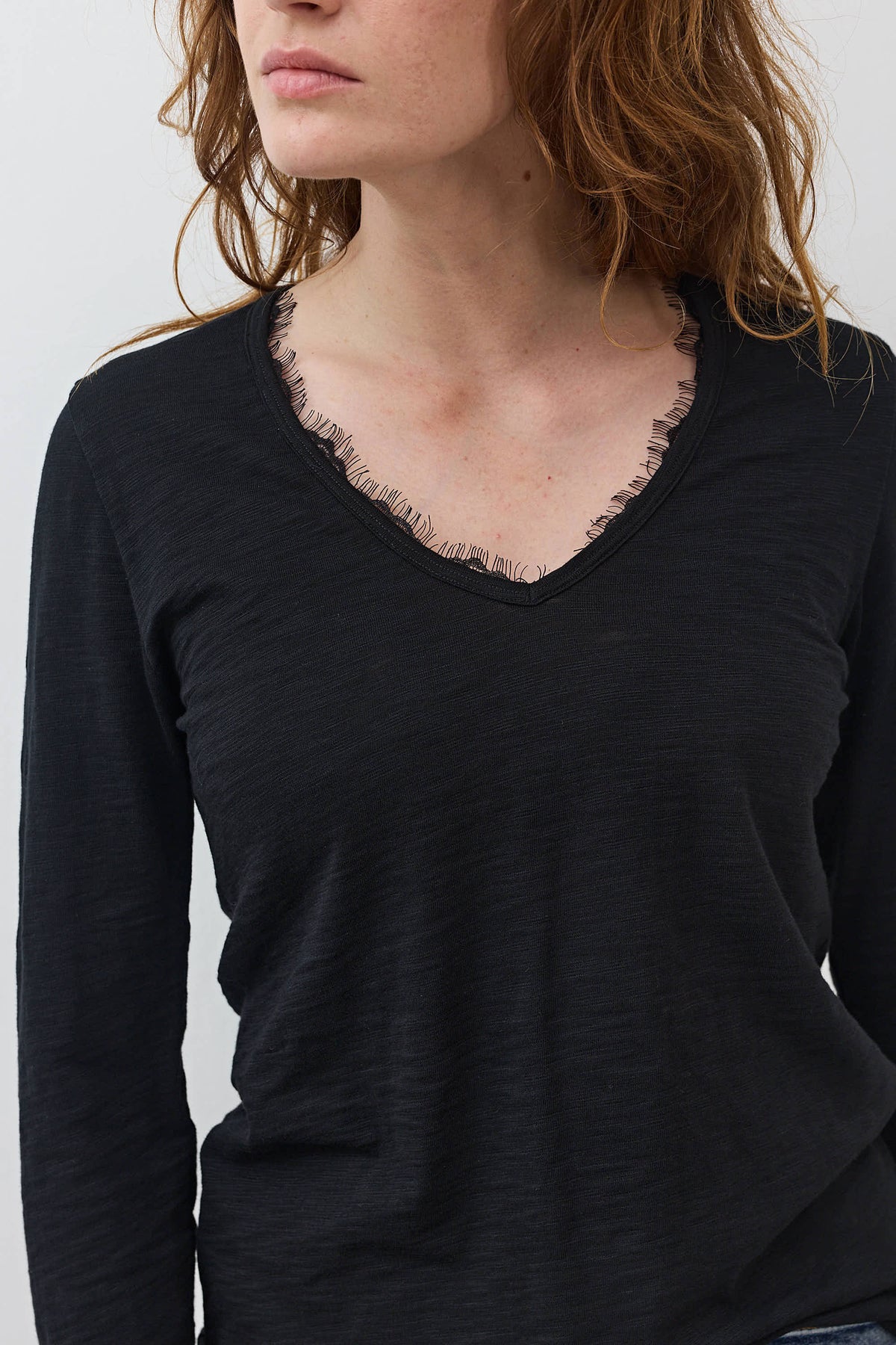 Black long-sleeve V-neck top with lace trim neckline detail