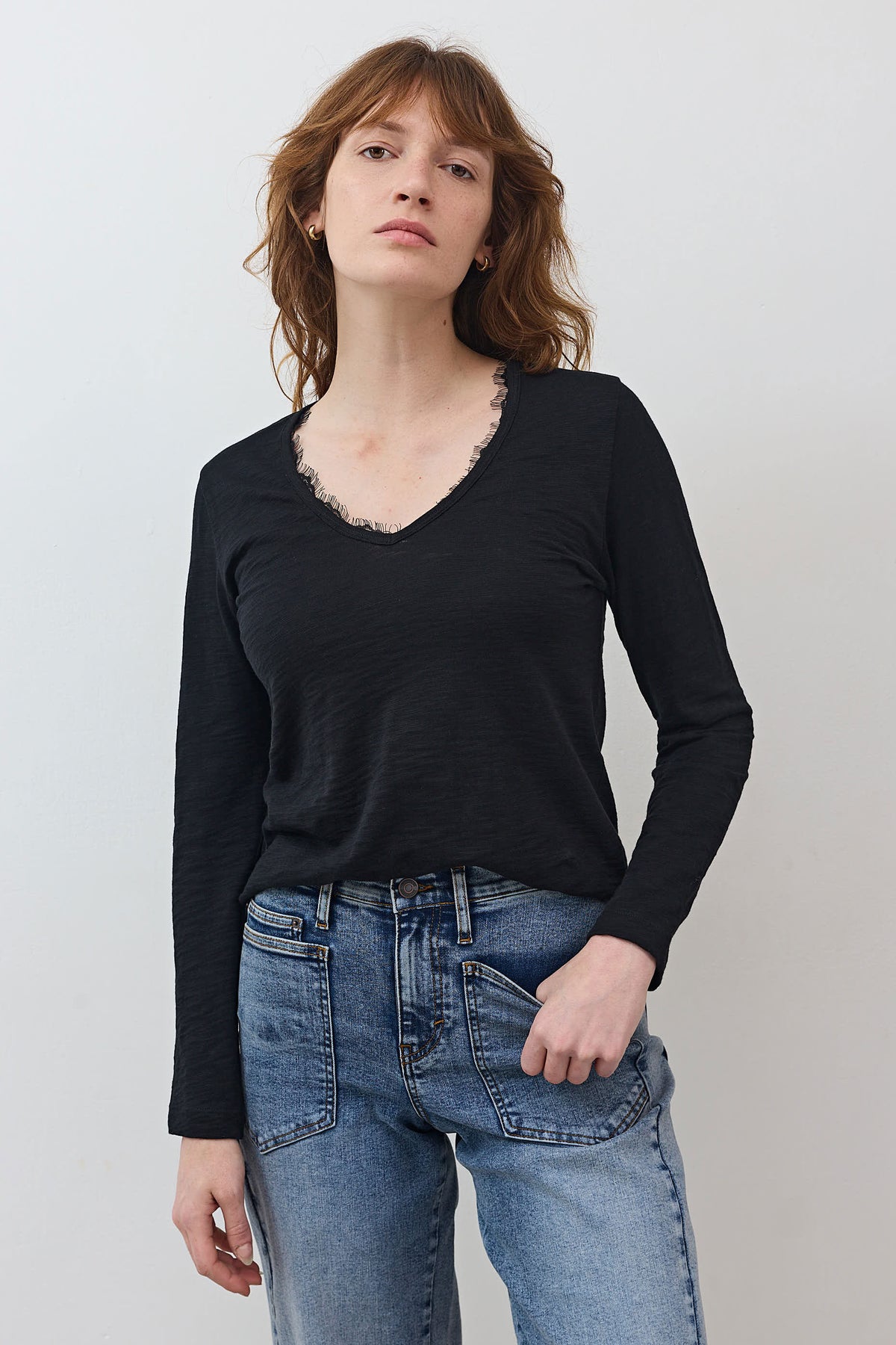 Black lace-trim V-neck long-sleeve top with denim jeans, front close-up
