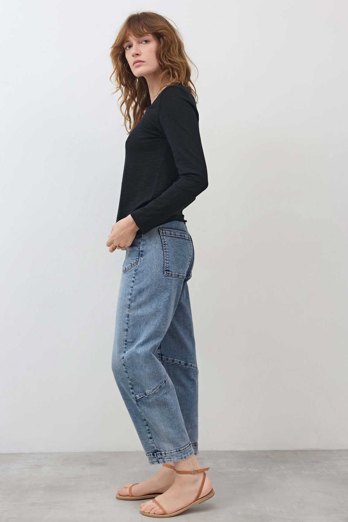 Black long-sleeve V-neck top with lace trim, worn with light-wash jeans