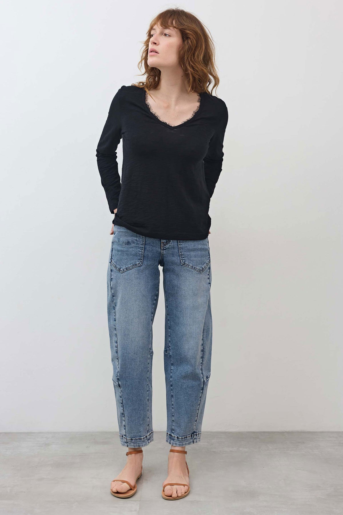 Black long-sleeve V-neck top with lace neckline trim, full-body front view