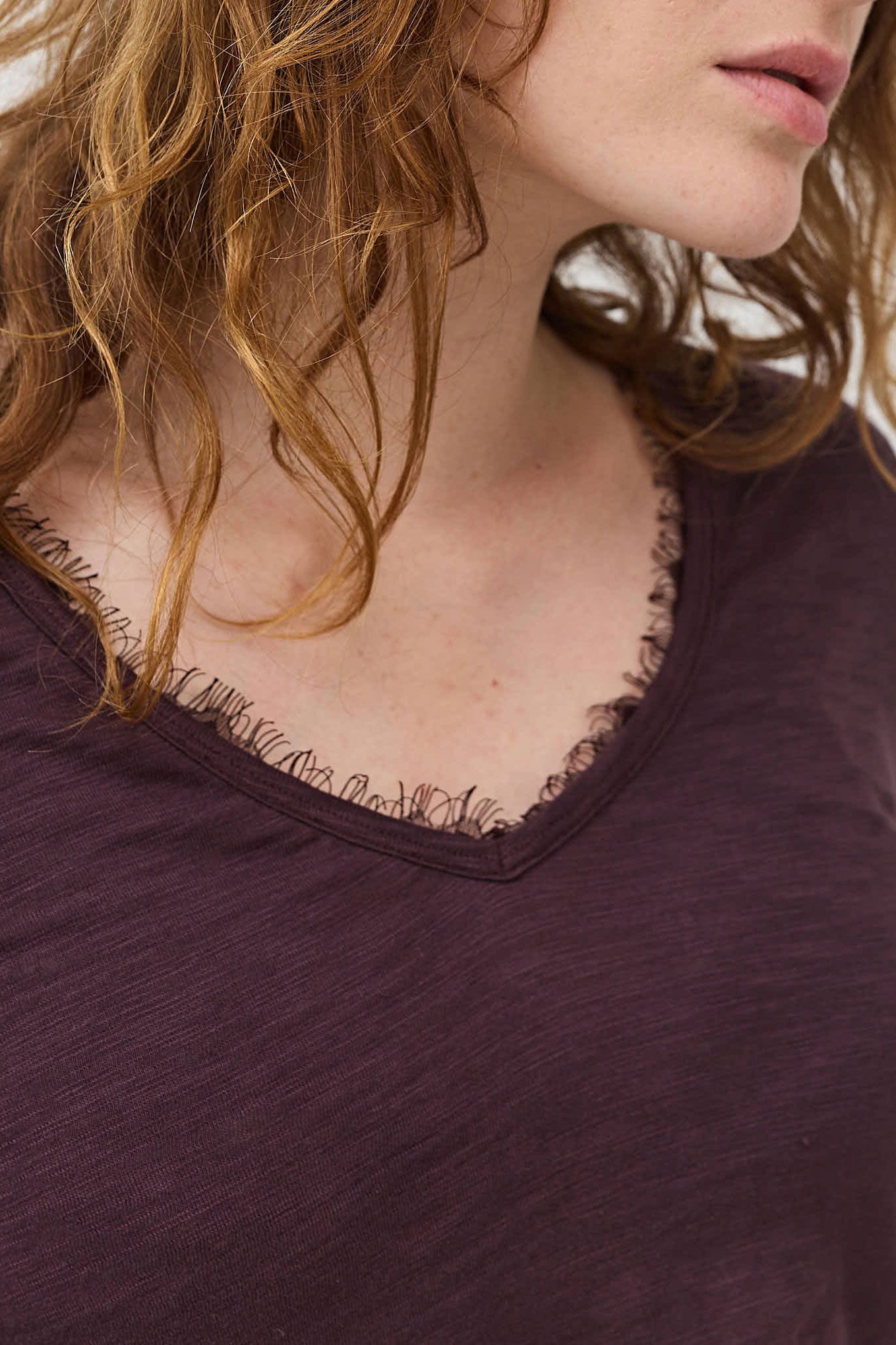Close-up of lace-trim V-neck on dark plum long sleeve top