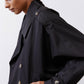 Black oversized nylon trench close-up with double row buttons and shoulder yoke detail.