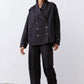 Black oversized nylon trench with double-breasted snaps and flap pockets, long sleeves.