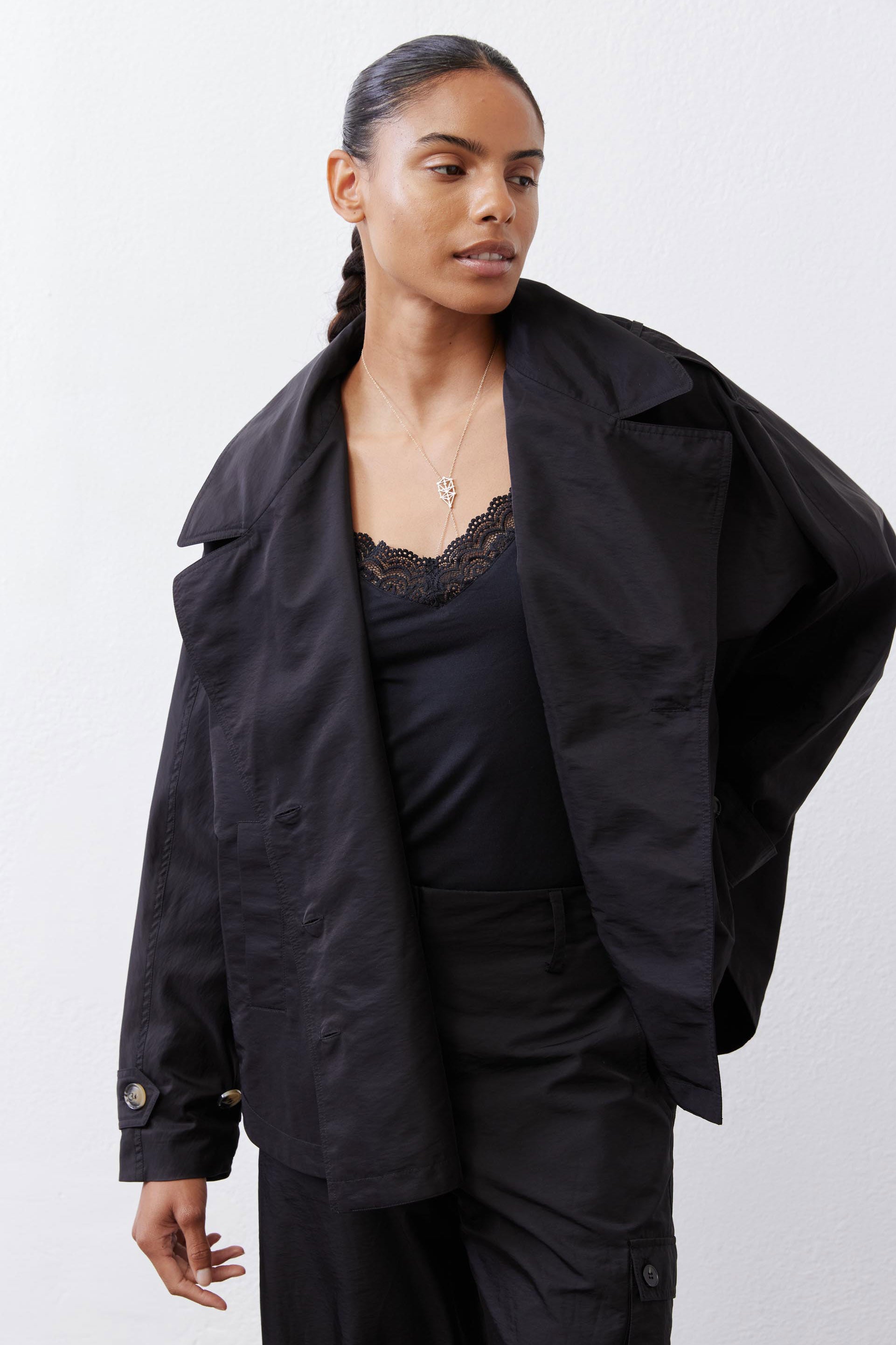 Black oversized nylon trench with open front, snap details, and flap pocket at chest.
