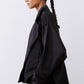 Black oversized nylon trench from side with large shoulder yoke and long cuffed sleeve.