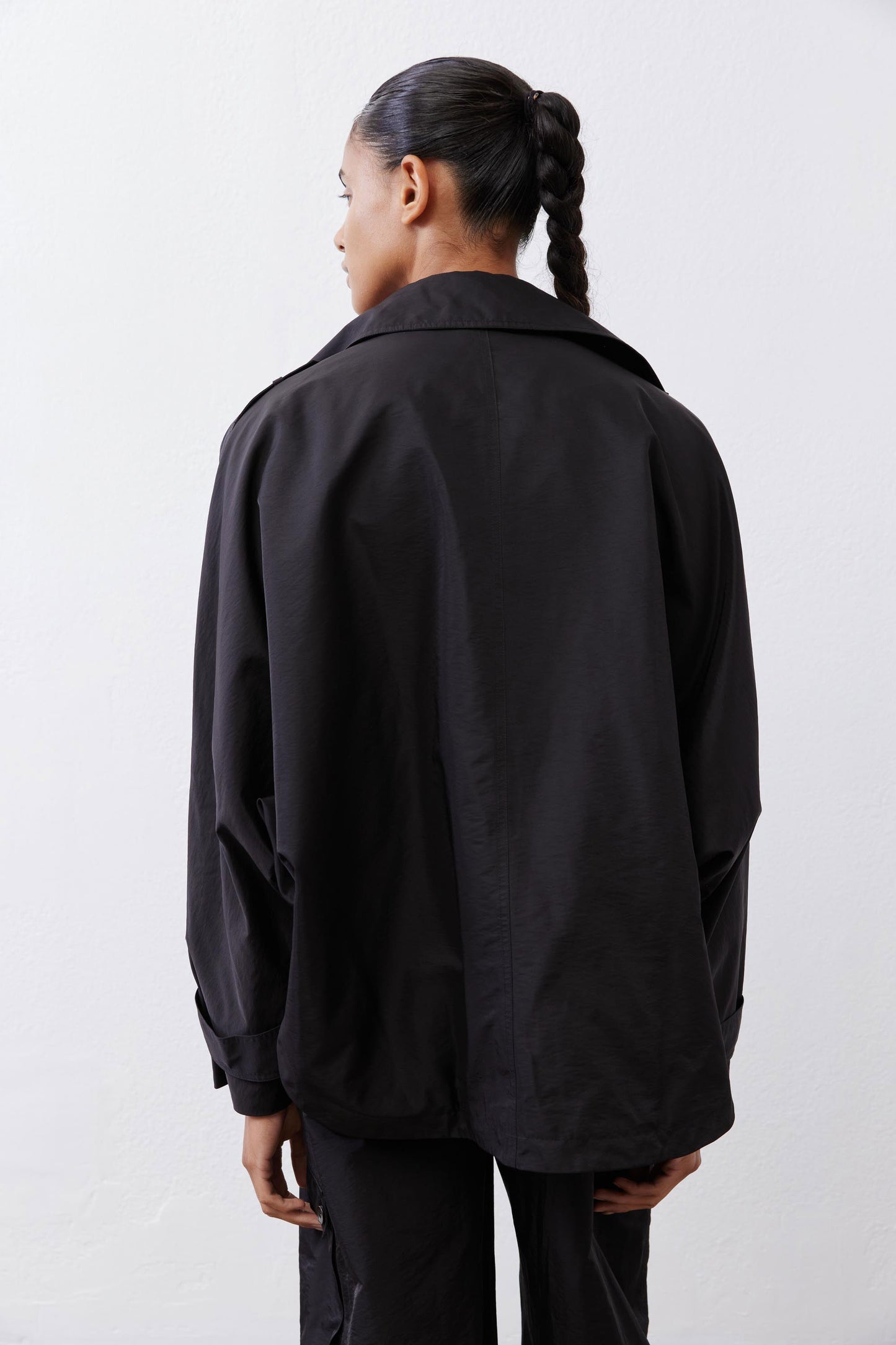 Black oversized nylon trench back view with roomy shoulders and side seam detail.
