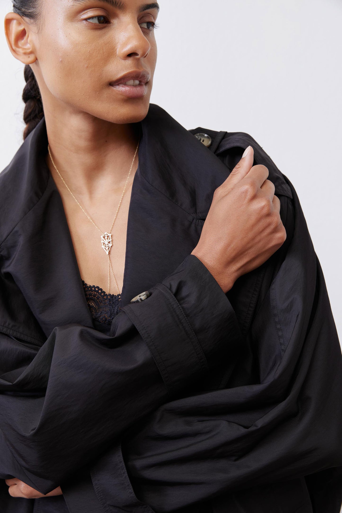 Black oversized nylon trench close-up with textured buttons, lapel collar, and pocket flap.