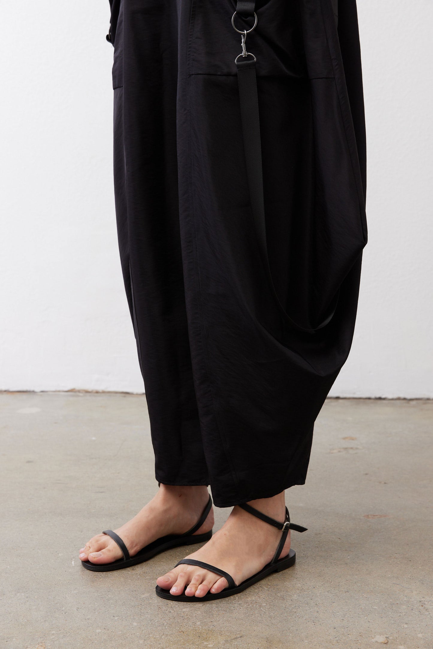Black wide-leg parachute pants with ankle-cropped cuffs and side pocket hardware.