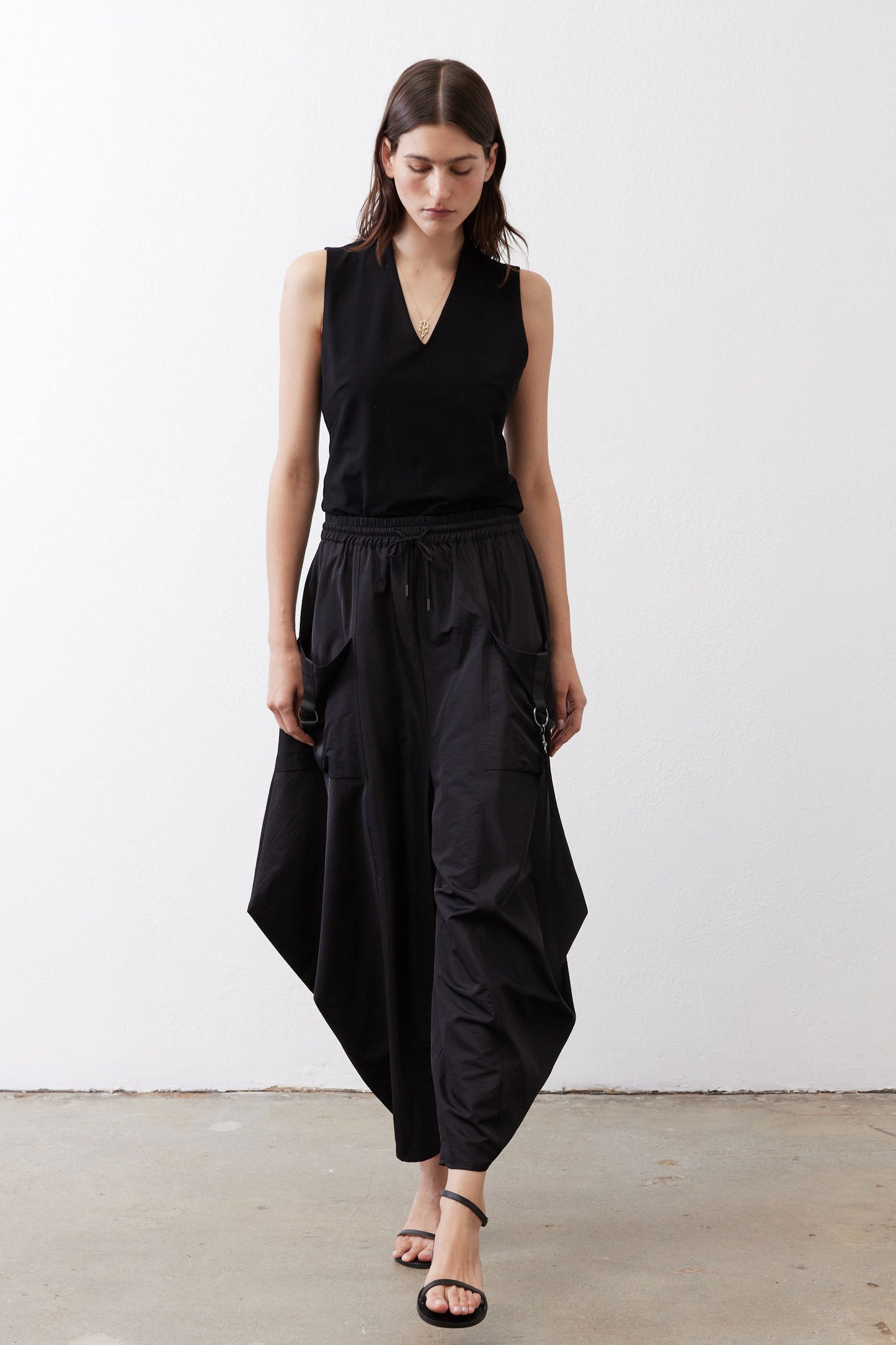 Black wide-leg parachute pants with elastic waist, cargo pockets, and ankle-length drape.
