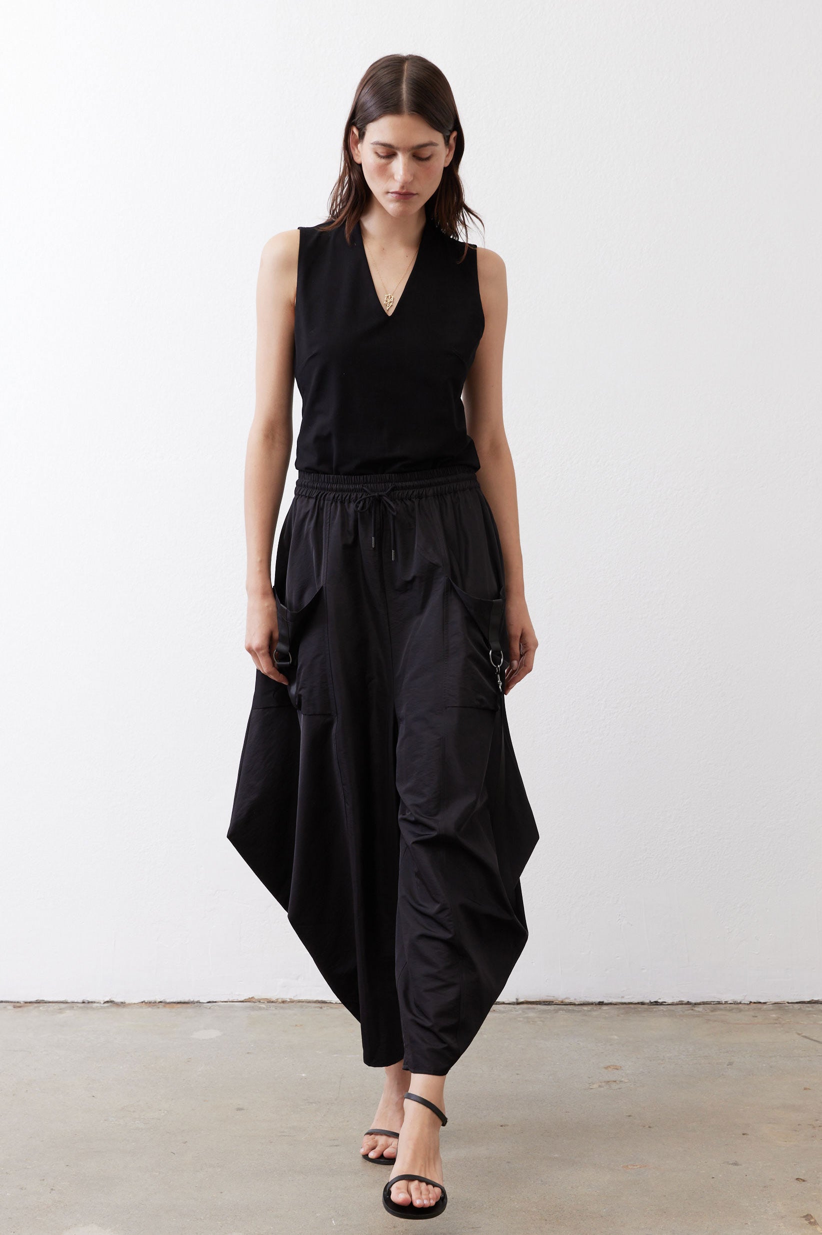 Black wide-leg parachute pants with elastic waist, cargo pockets, and ankle-length drape.