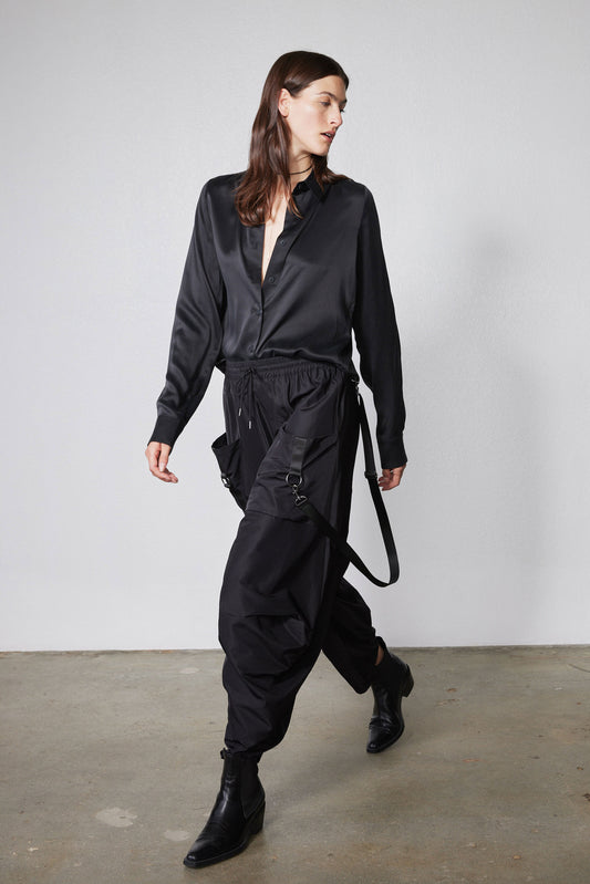 Black wide-leg parachute pants with drawstring waist and dangling side straps