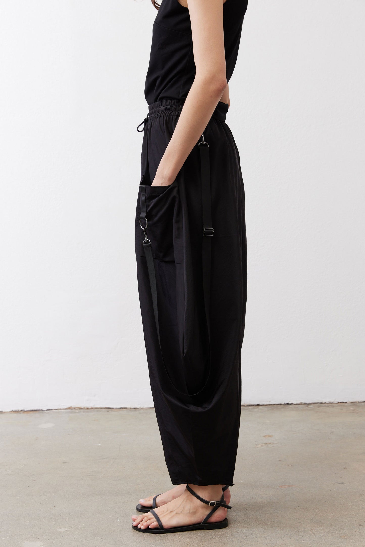 Black wide-leg parachute pants with side pocket detail and adjustable drawstring.