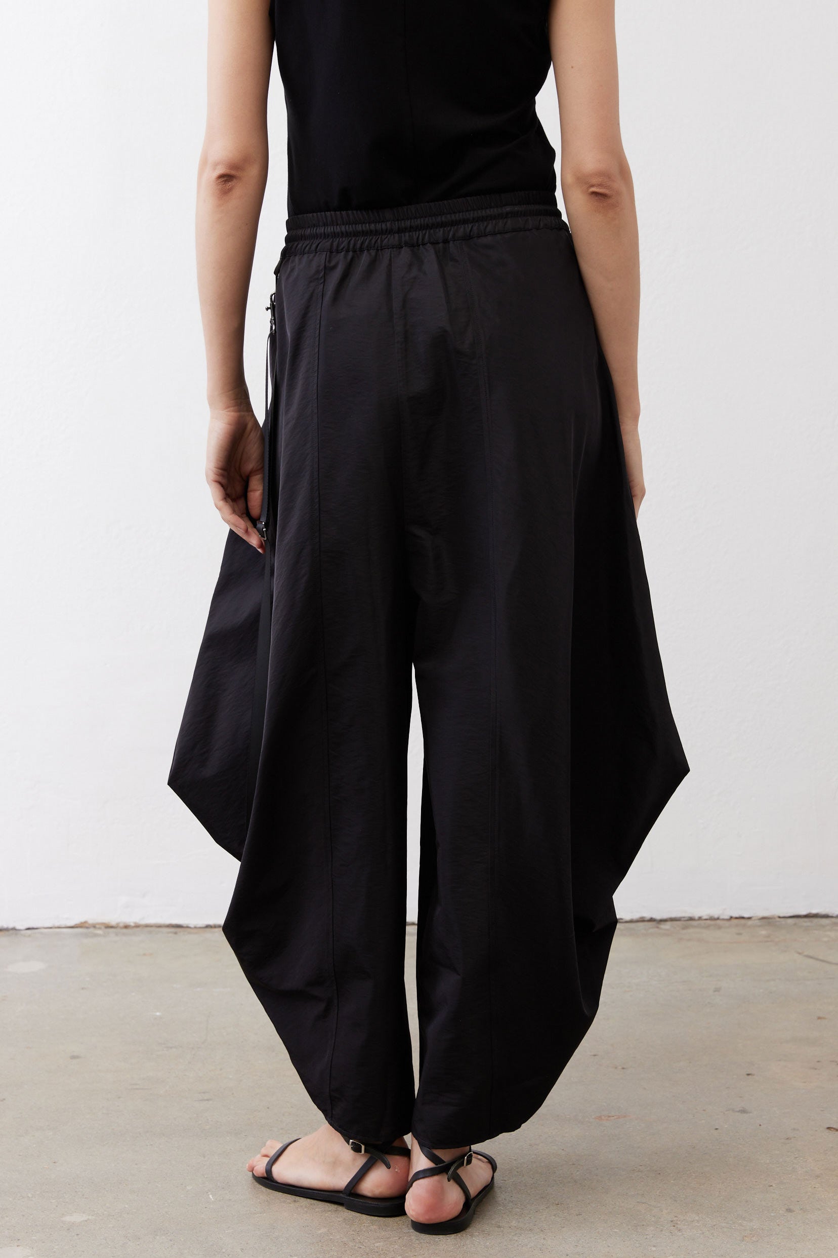 Black wide-leg parachute pants with elastic waist and large side cargo pockets.