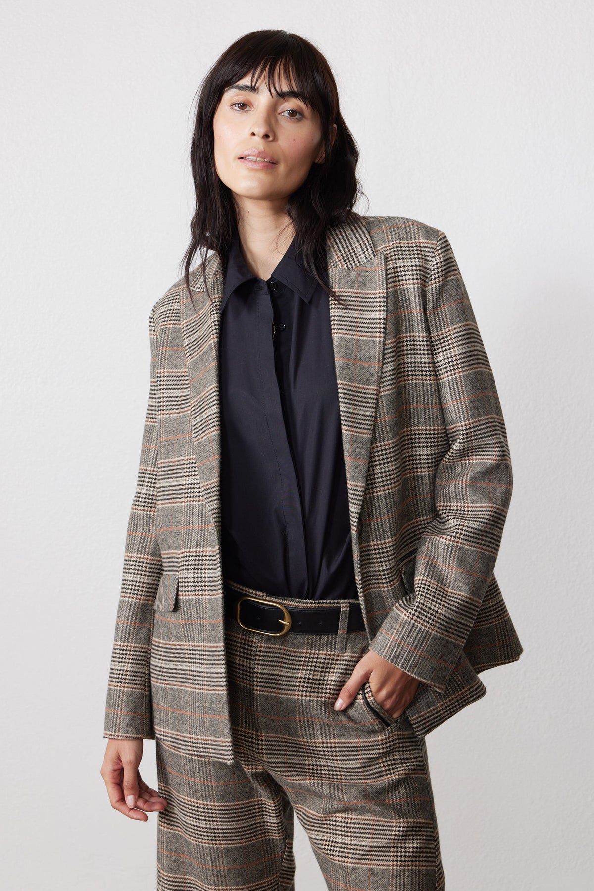 Brown plaid blazer with black elbow patches and dark buttoned shirt