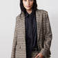 Brown plaid blazer with black elbow patches and notch lapel over dark shirt