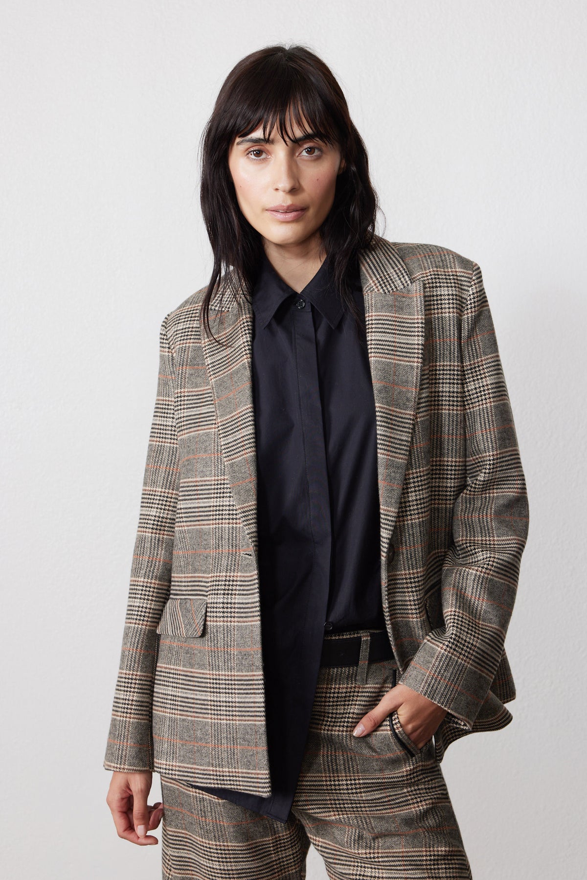 Brown plaid blazer with black elbow patches and notch lapel over dark shirt